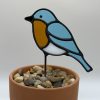 blue bird stained glass plant stake. blue body, dark amber belly, white underbelly.